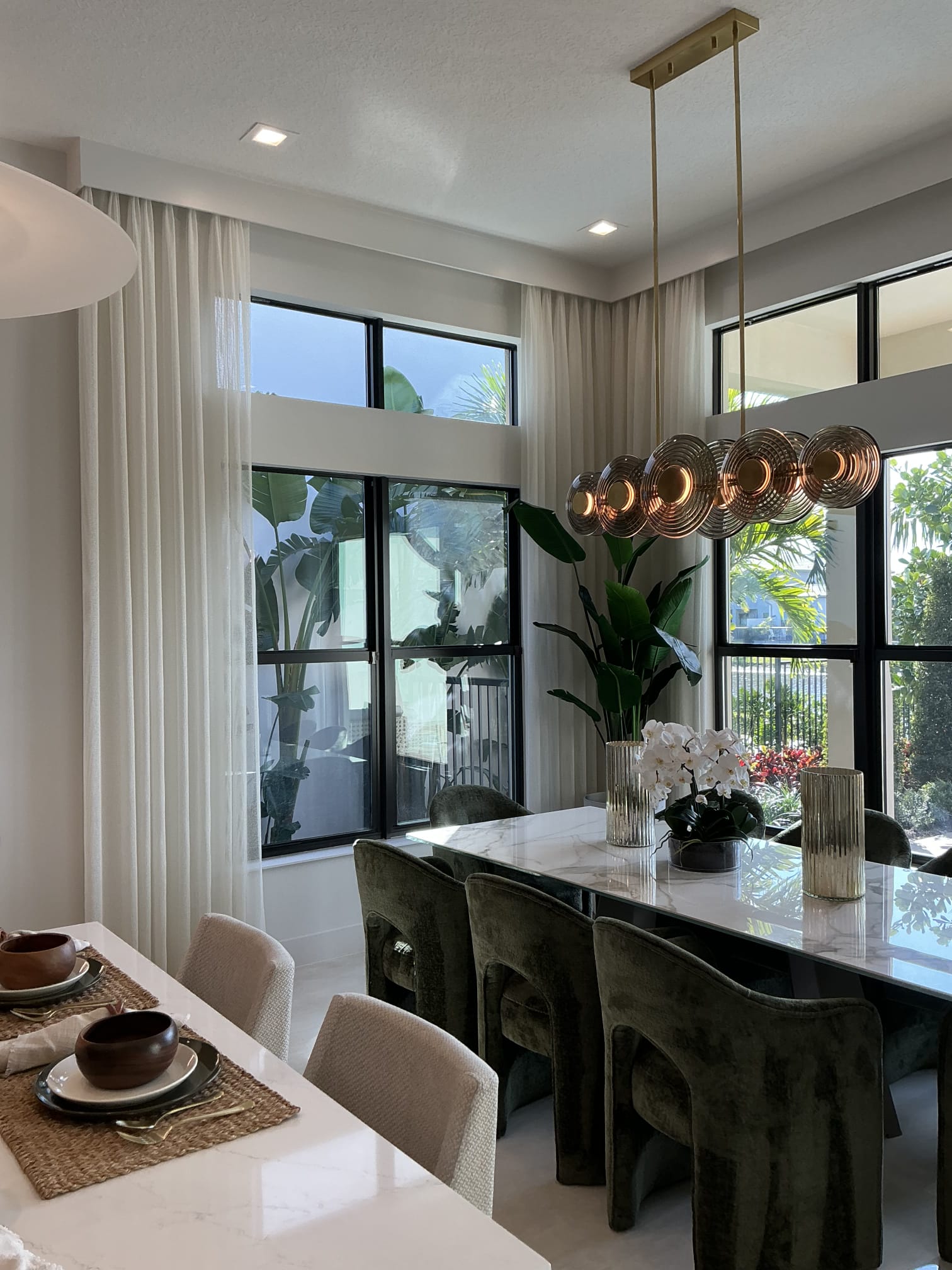Floor-length white sheer drapery on black-framed dining windows