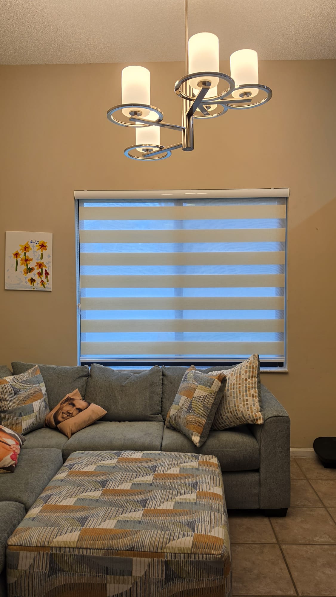 White zebra blind above a living-room sofa in evening light