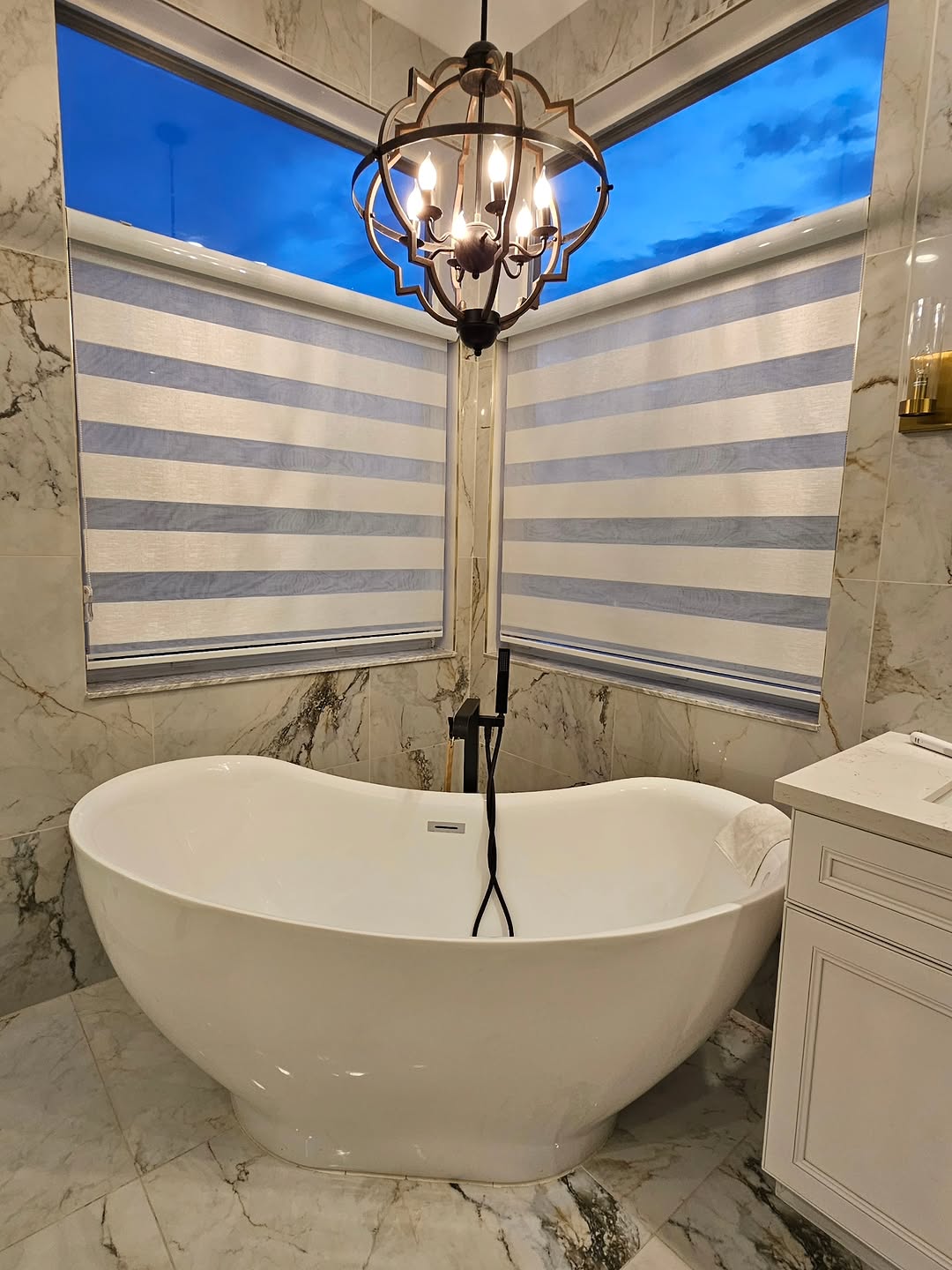 Pair of zebra blinds in a marble bathroom around a freestanding tub