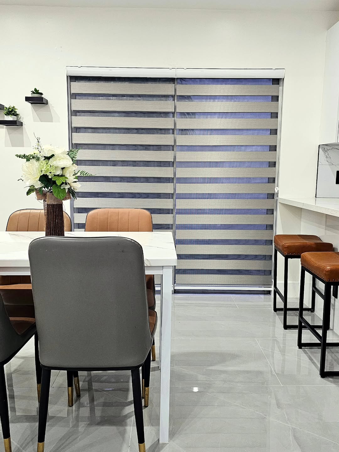 Pair of grey zebra blinds behind a dining table